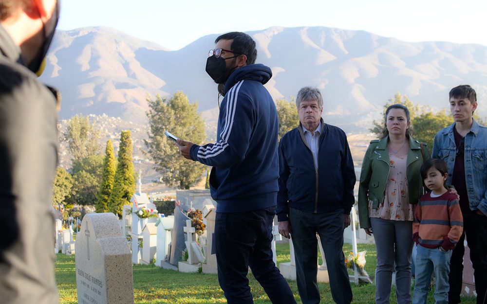 Rodaje de Amores incompletos en un panteón: el director da indicaciones al elenco entre las tumbas, con montañas al fondo