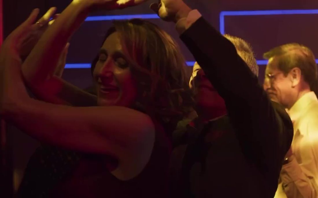 Fotograma de Bailando solo: parejas bailando en la pista con luz roja y morada