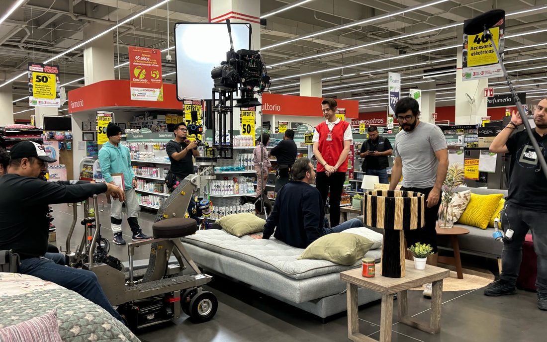 Rodaje de Bailando solo dentro de una tienda departamental, con la cámara sobre dolly y el equipo alrededor de una sala de muestra